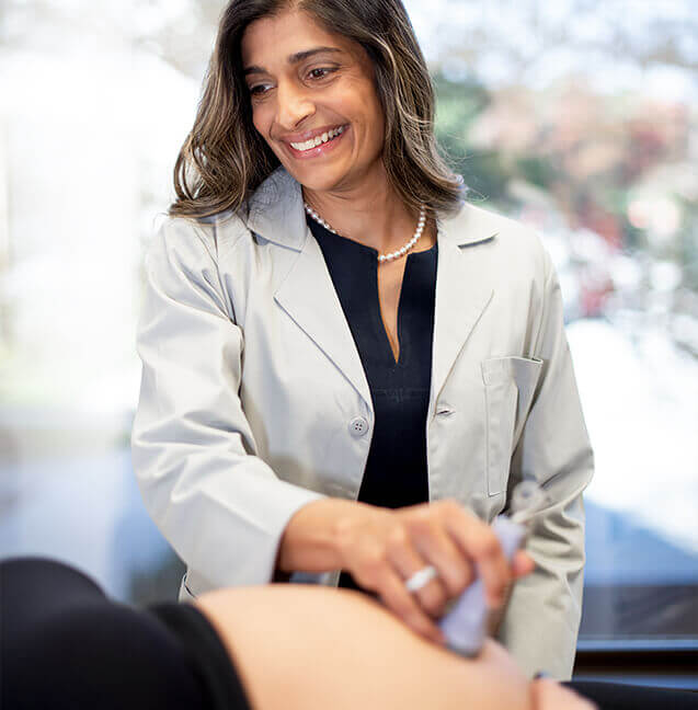 obgyn doctor performing fetal ultrasound pregnant woman's belly