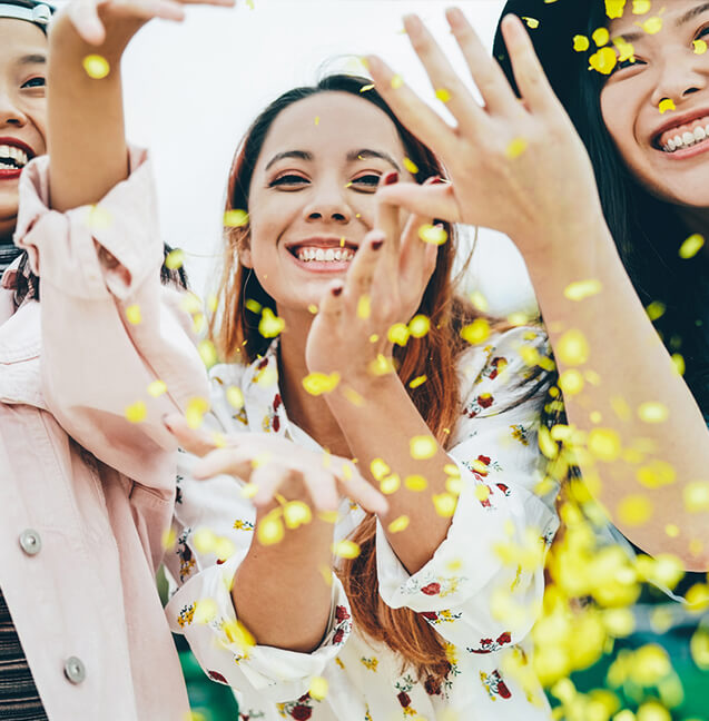 happy women playing with yellow confetti